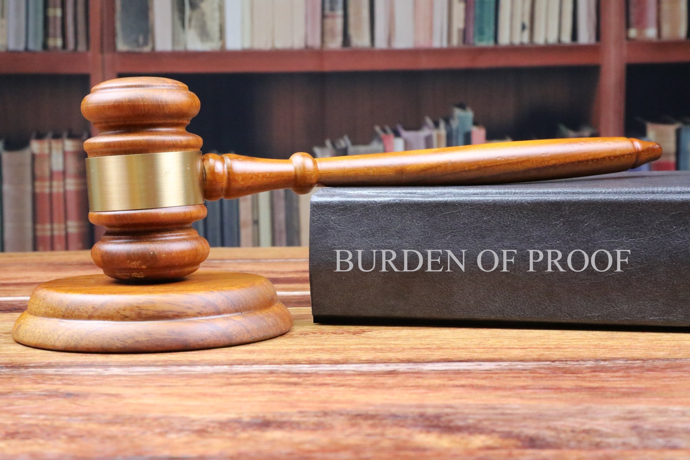 gavel resting on book entitled "burden of proof"
